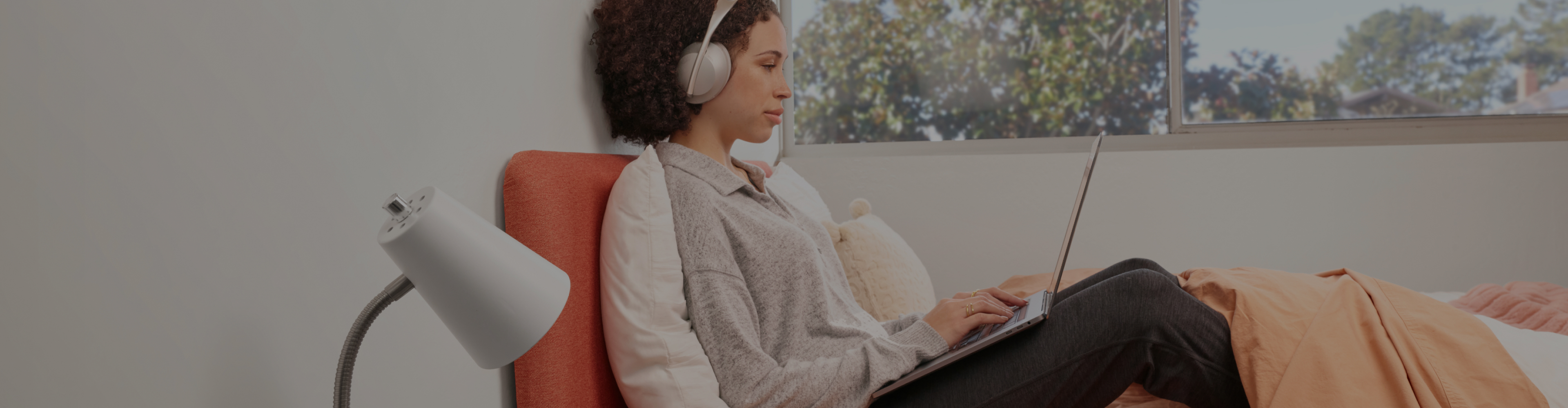 Person sitting on a couch with headphones and a laptop